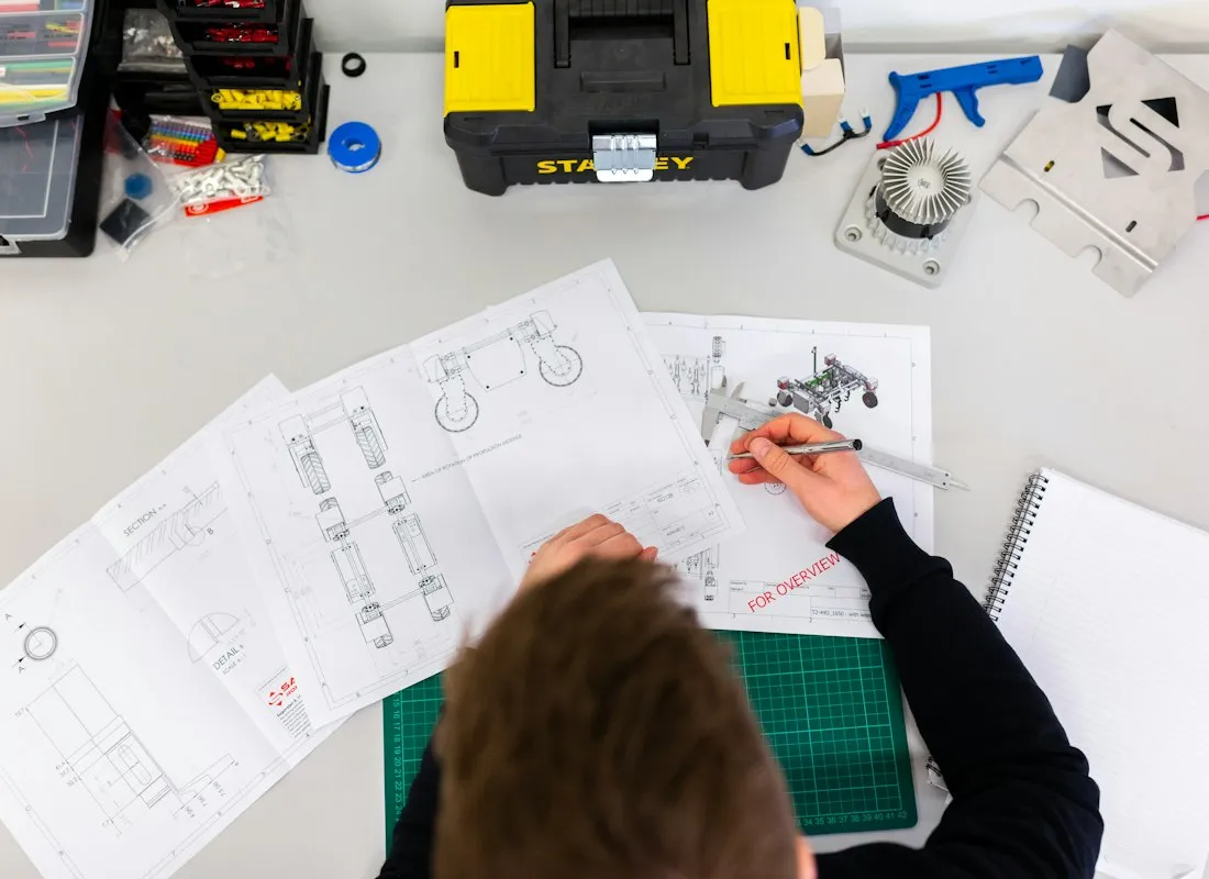 Medewerker werkt aan technische tekeningen op een werktafel